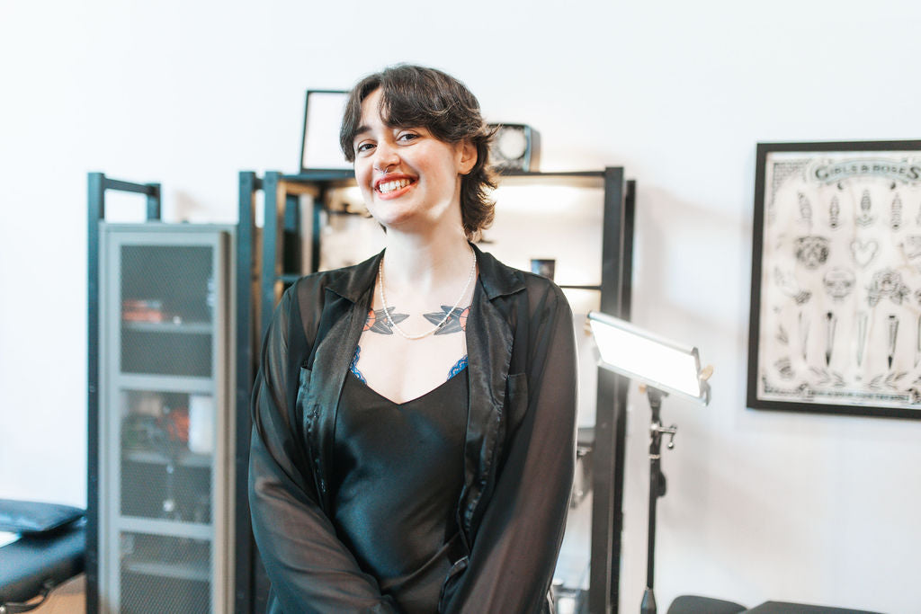 Tattoo artist standing in a tattoo studio in Portland, Oregon with tattoo supplies behind them